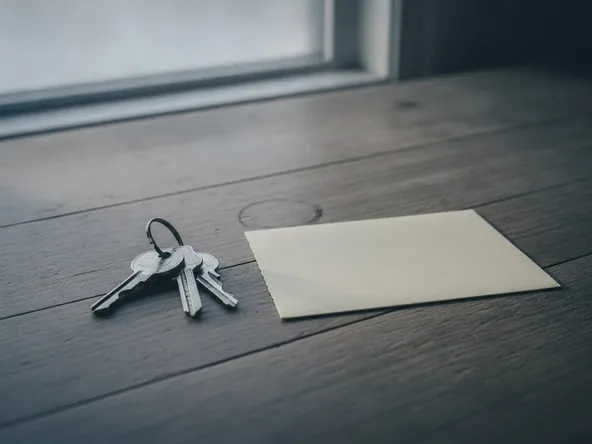 A ring of house keys on a wooden kitchen table beside a blank note